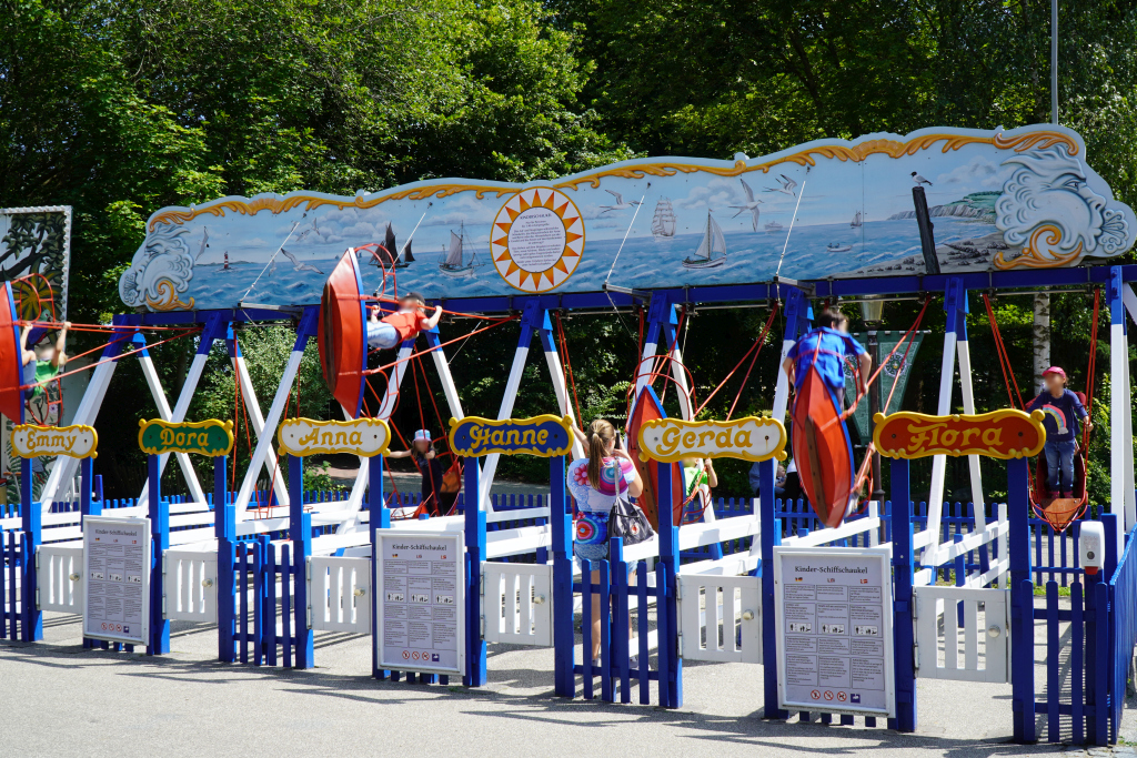 Die Kinder-Schiffschaukel mit Kindern auf den Schiffen. Die einzelnen Schaukeln haben Frauennamen.