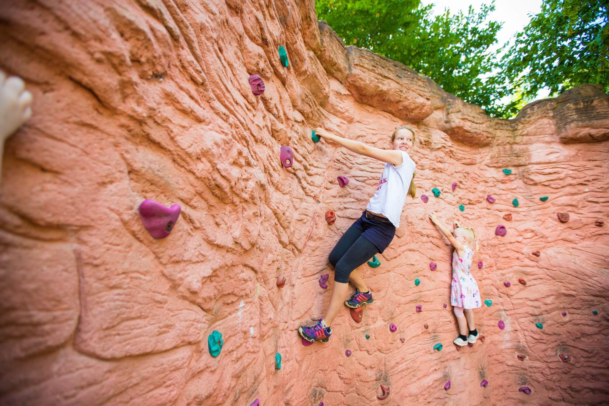 Zwei Mädchen sind an der Kletterwand. Die Große ist etwas höher, als die Kleine.