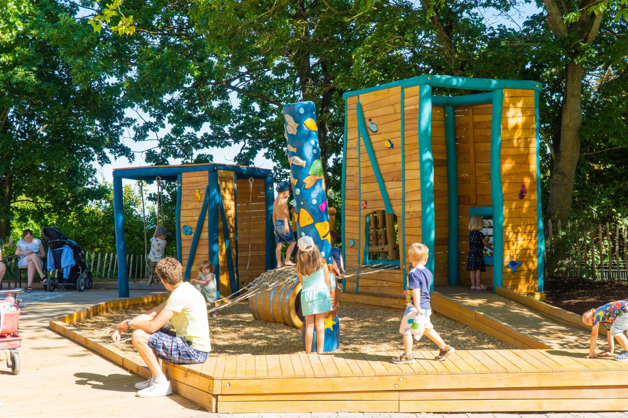 Ganz viele Kinder auf dem Inklusionspielplatz Patio del Mar. Ein Mann sitzt und wartet.