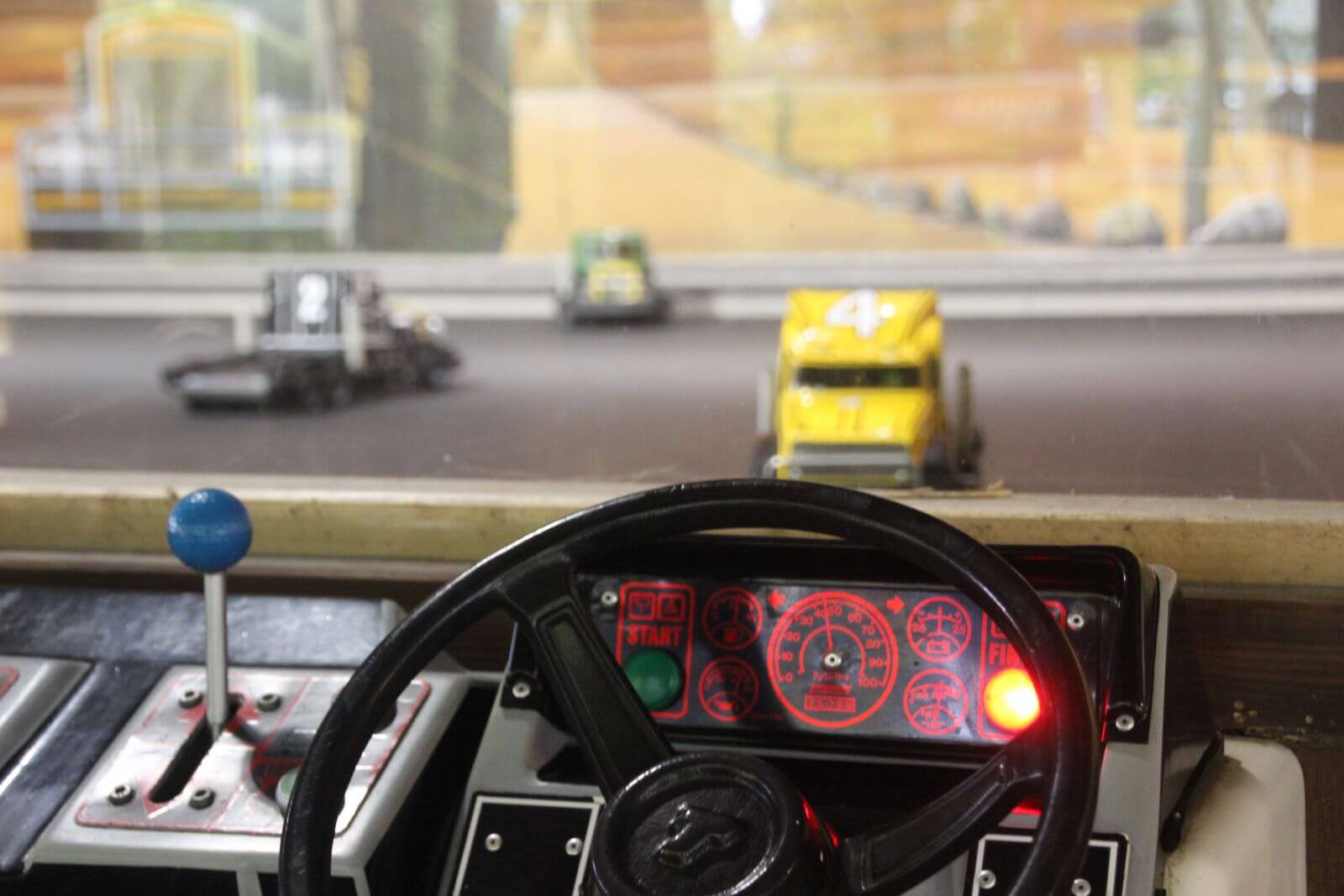 Mit einem Lenkrad, einem Schalter und einer Anzeige steuert man ferngesteuerte Super Trucks.