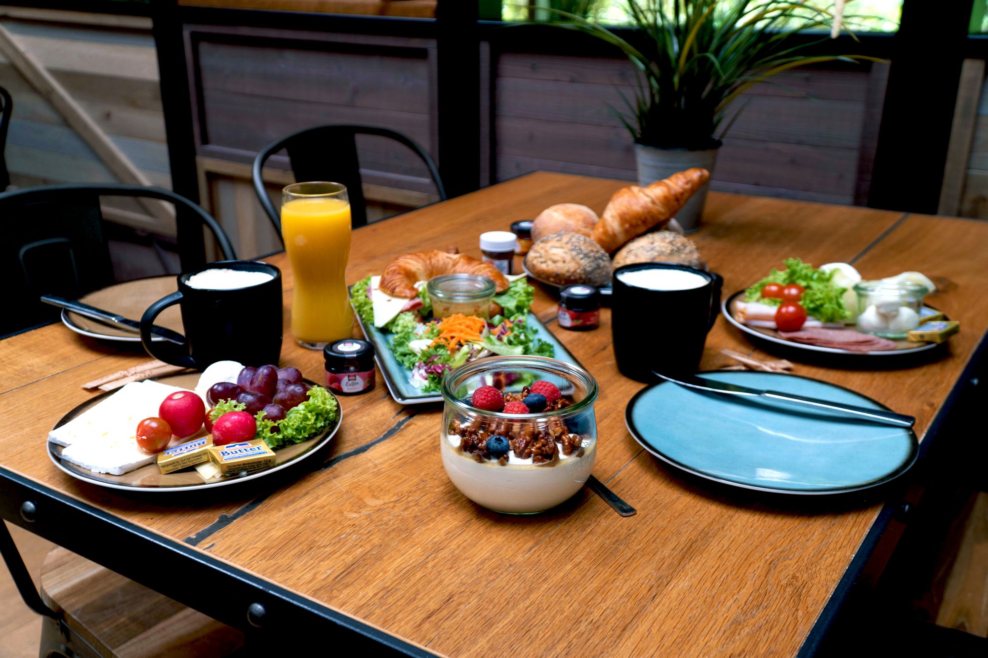 Ein Tisch gedeckt für zwei. Mit verschiedene Frühstückspeisen und Getränken.