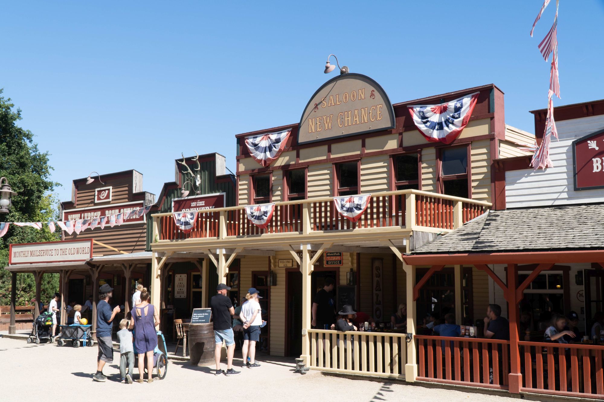 Das Gebäude des Saloon New Chance von außen. Auf der Terrasse sitzen Gäste und essen.