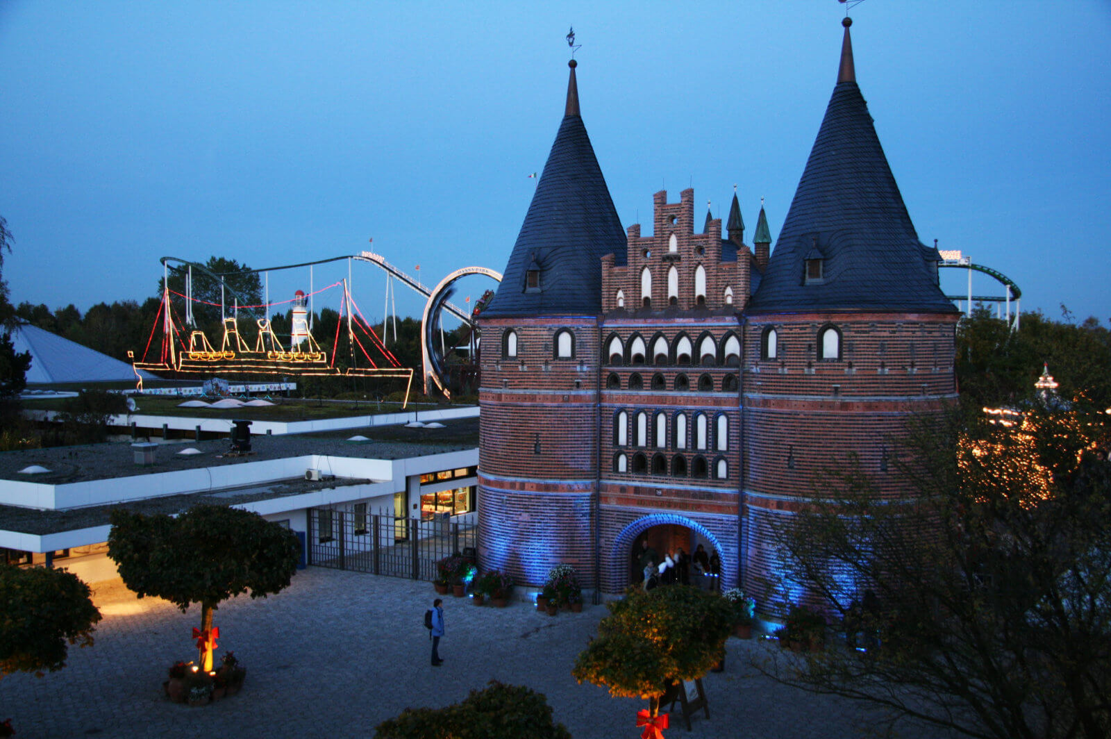 Das Holstentor am Abend. Es wird durch Lampen beleuchtet. Im Hintergrund sieht man Nessi.