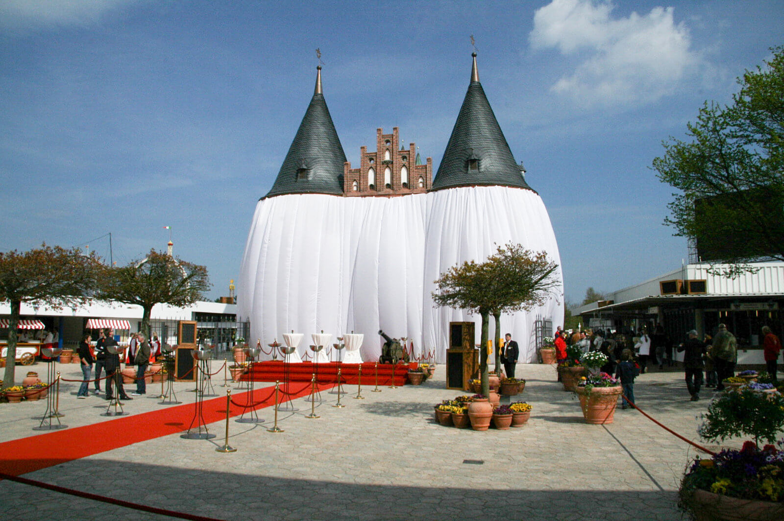 Das Holstentor komplett verhüllt. Ein roter Teppich für zu einer Empore mit drei Stehtischen.