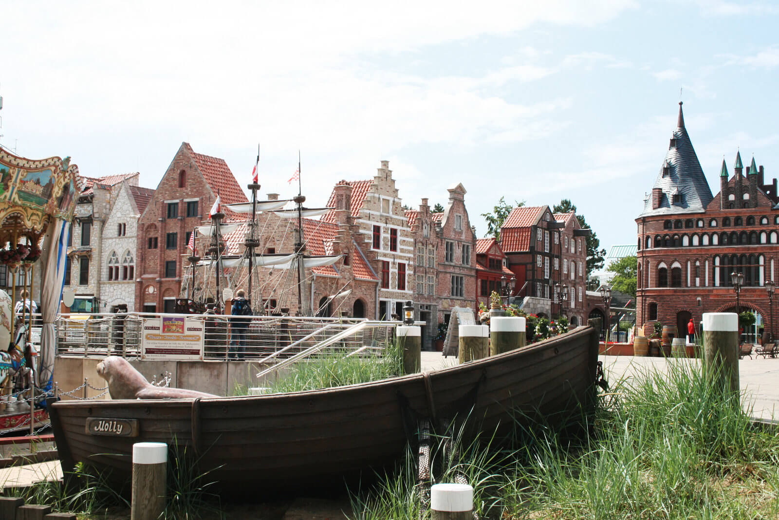 Ein Ruderboot liegt im Vordergrund. Im Hintergrund sind die Arcaden aus Brügge und Hamburg.