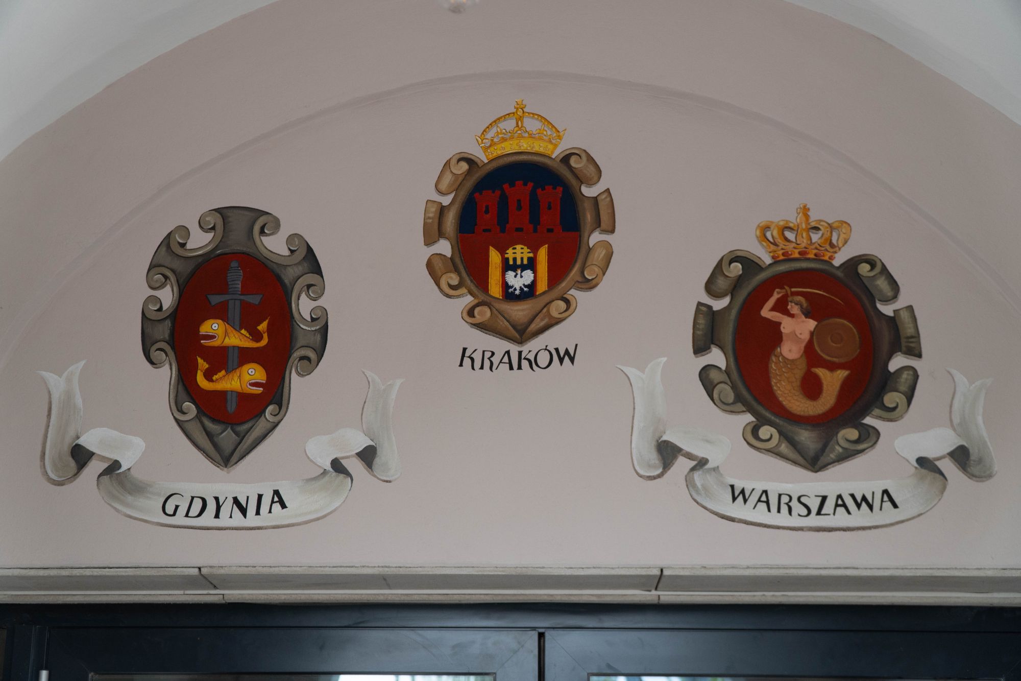 Über dem Eingang zum Weltumsegler befindet sich drei Wappen von Gdynia, Krakow und Warszawa.