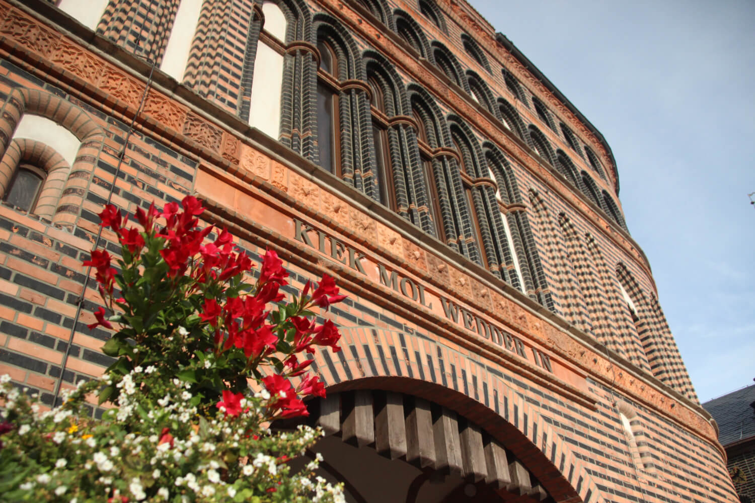 Das Holstentor des HANSA-PARKs von unten fotografiert. Davor ein Topf mit roten und weißen Blumen.