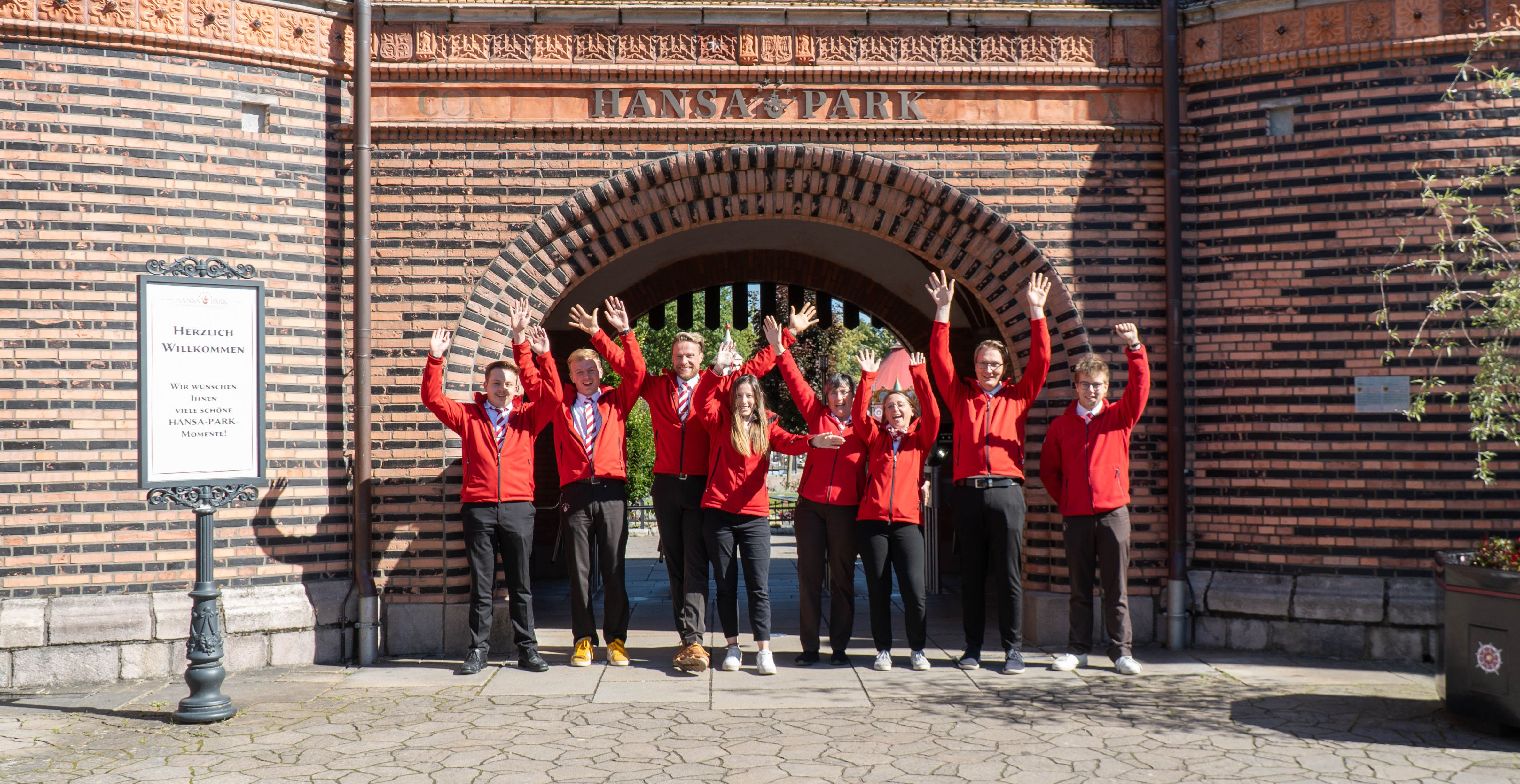 Vor dem Tor des Holstentors stehen Mitarbeiter und freuen sich.